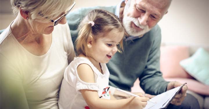 kid with grand parents reading a large book